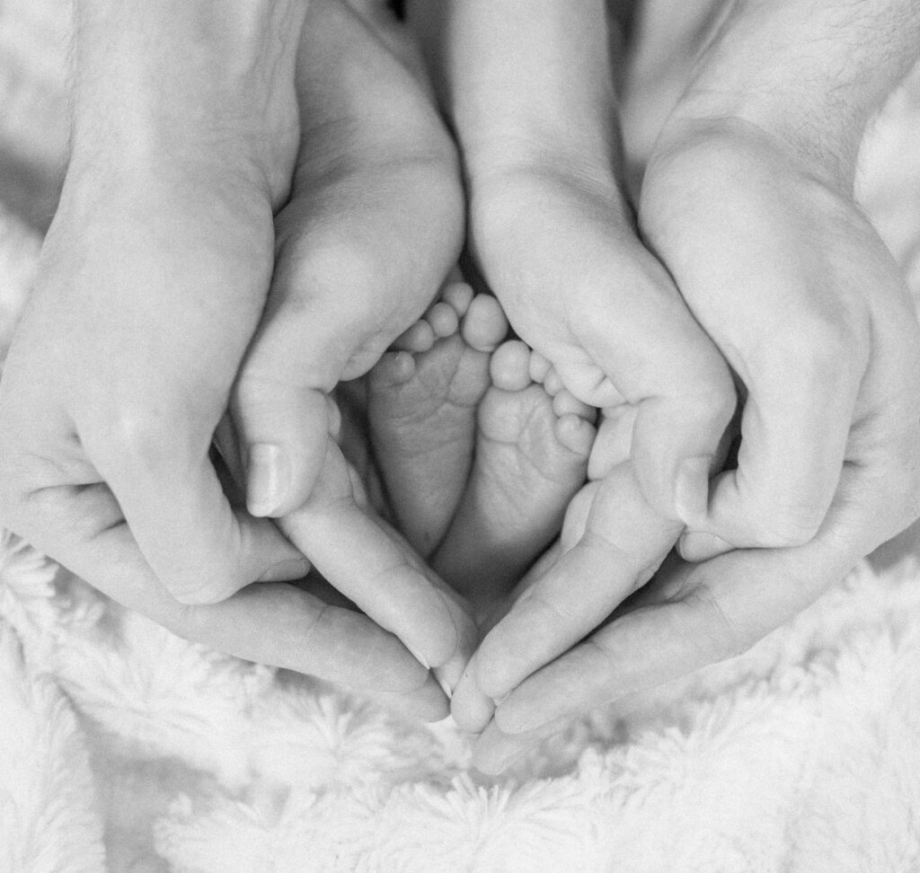 Dad cups mom's hands, which grasp newborn baby's feet