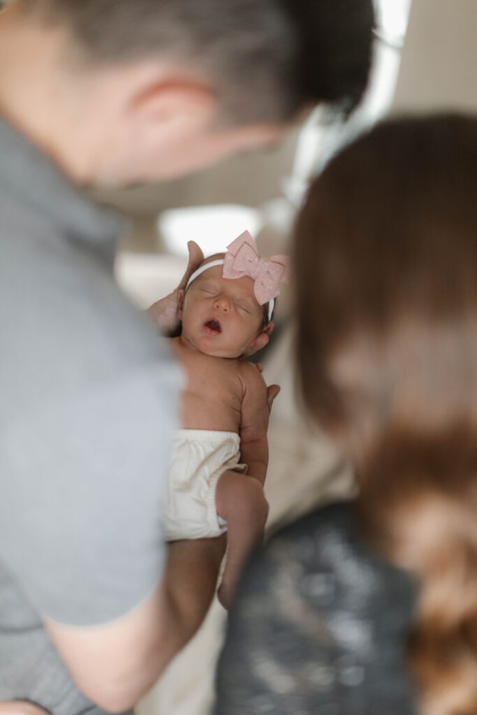 peering over mom and dad's shoulders looking down on baby