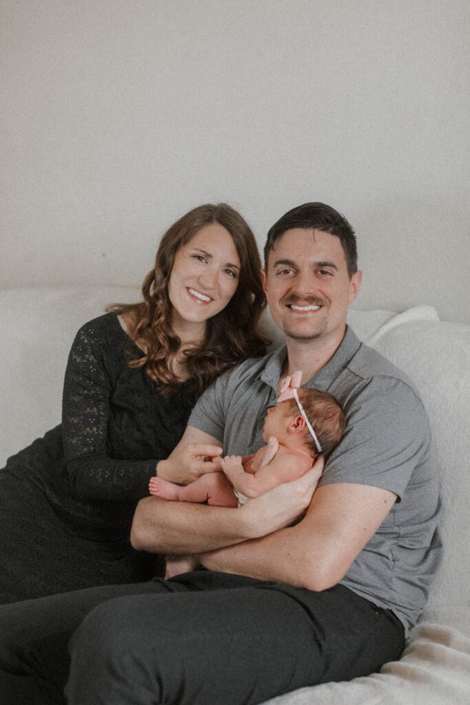 Mother and father embrace their baby on the couch in this relaxed Home Newborn Session
