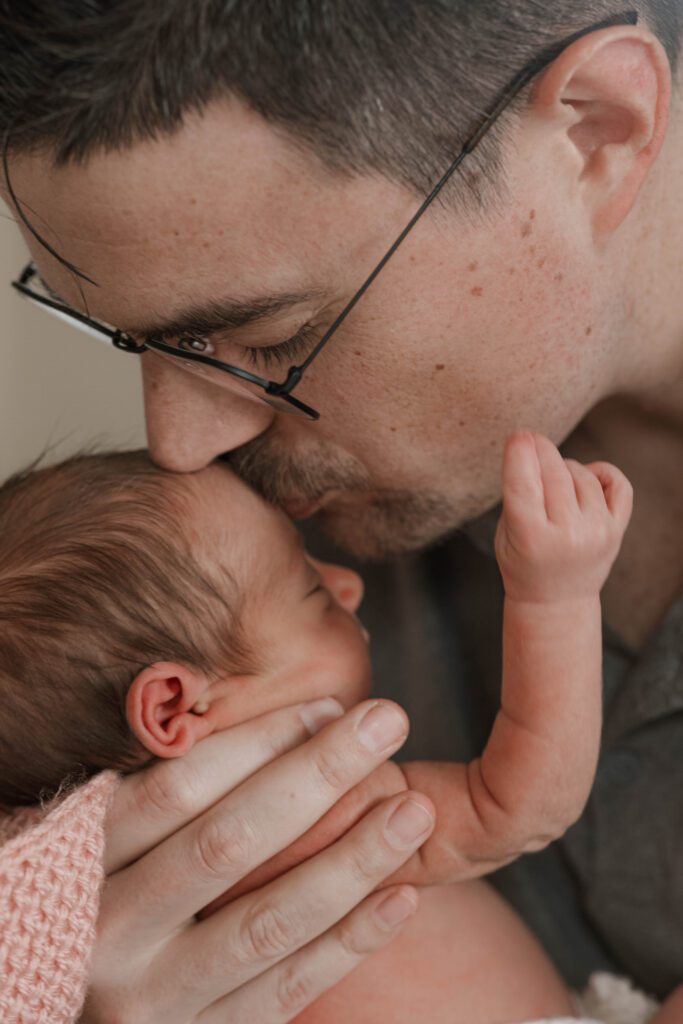 Dad gingerly kisses his baby's forehead during an in Home Newborn Session