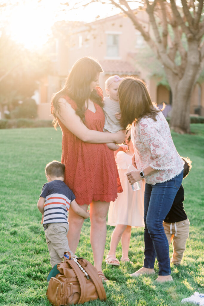 Haze photo of a mother and grandmother holding her baby while her children run around her