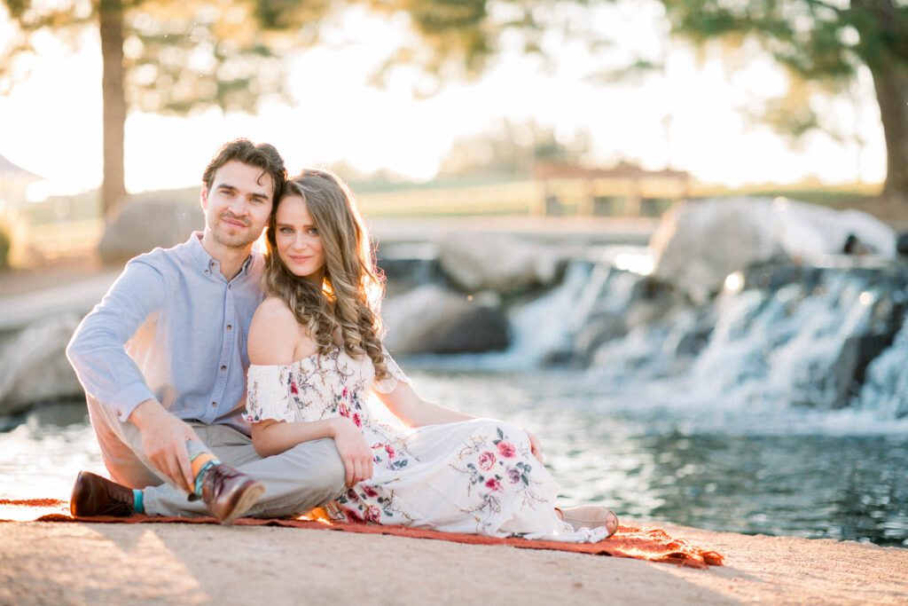 Cute couple found the right photographer, they sit in the sunset in front of a waterfall