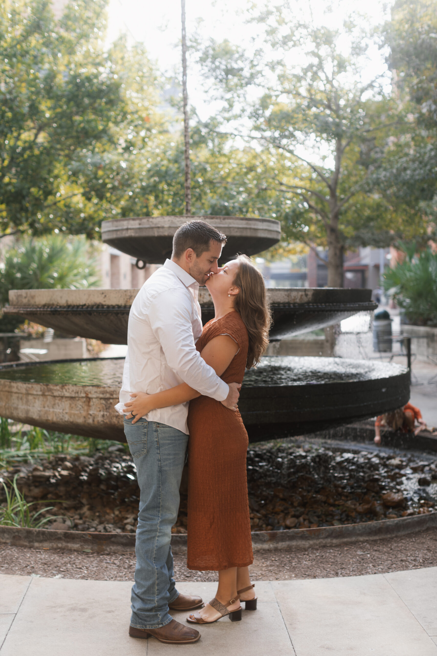 husband and wife kiss in front of the fountain at the pearl