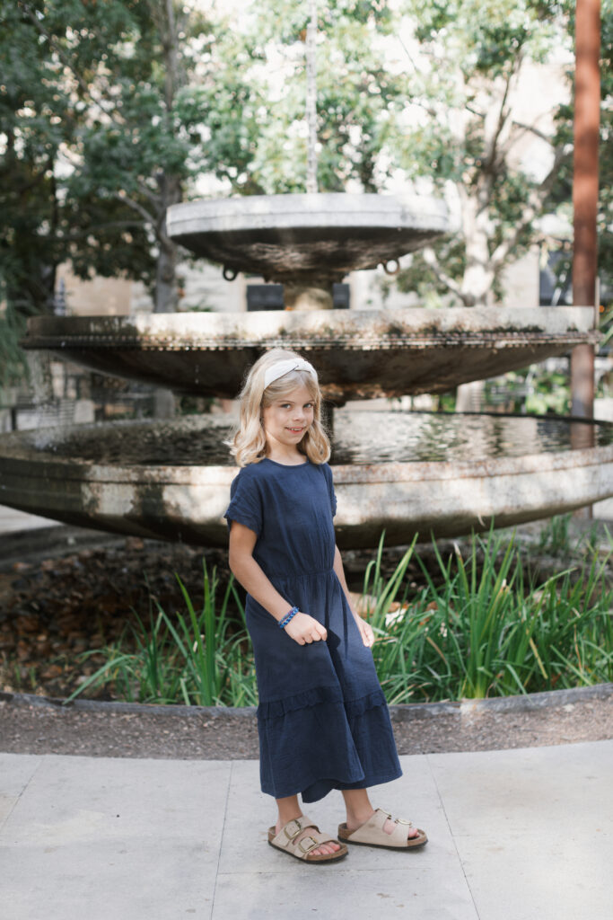 Girl stands in front of fountain at the pearl