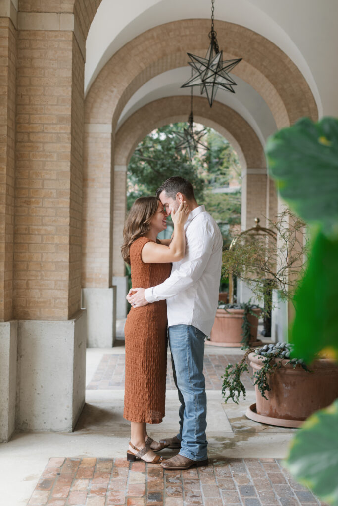 Husband and wife intimately hold each other under the bricked archways.