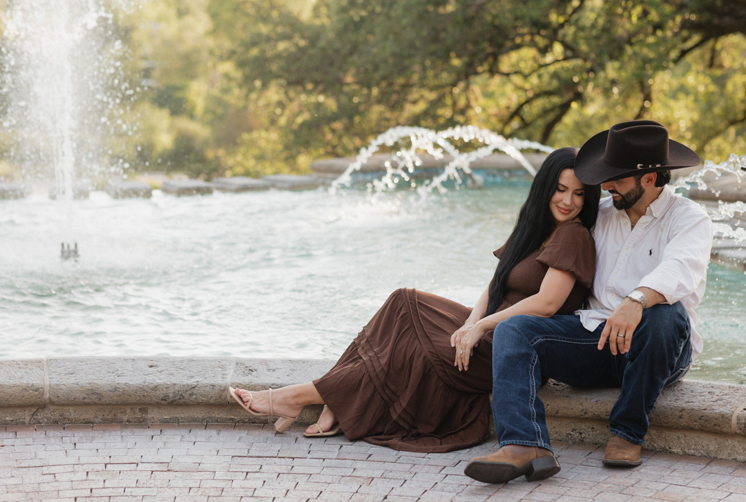 wife intimately leans on husband in front of the fountain
