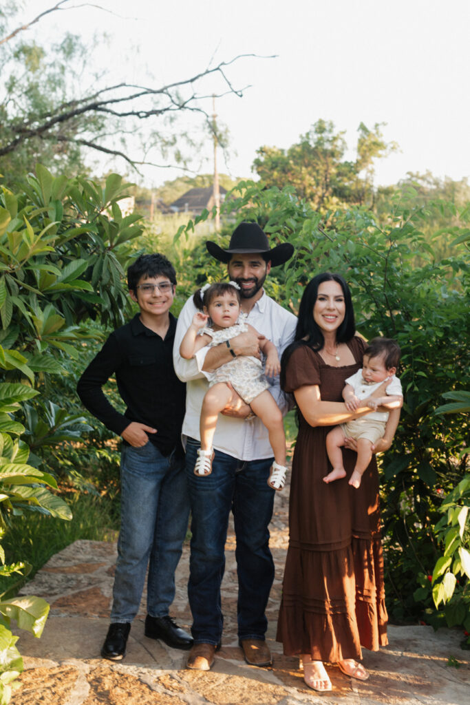 Family Photos at the McNay Museum, the family stands in front of the foliage
