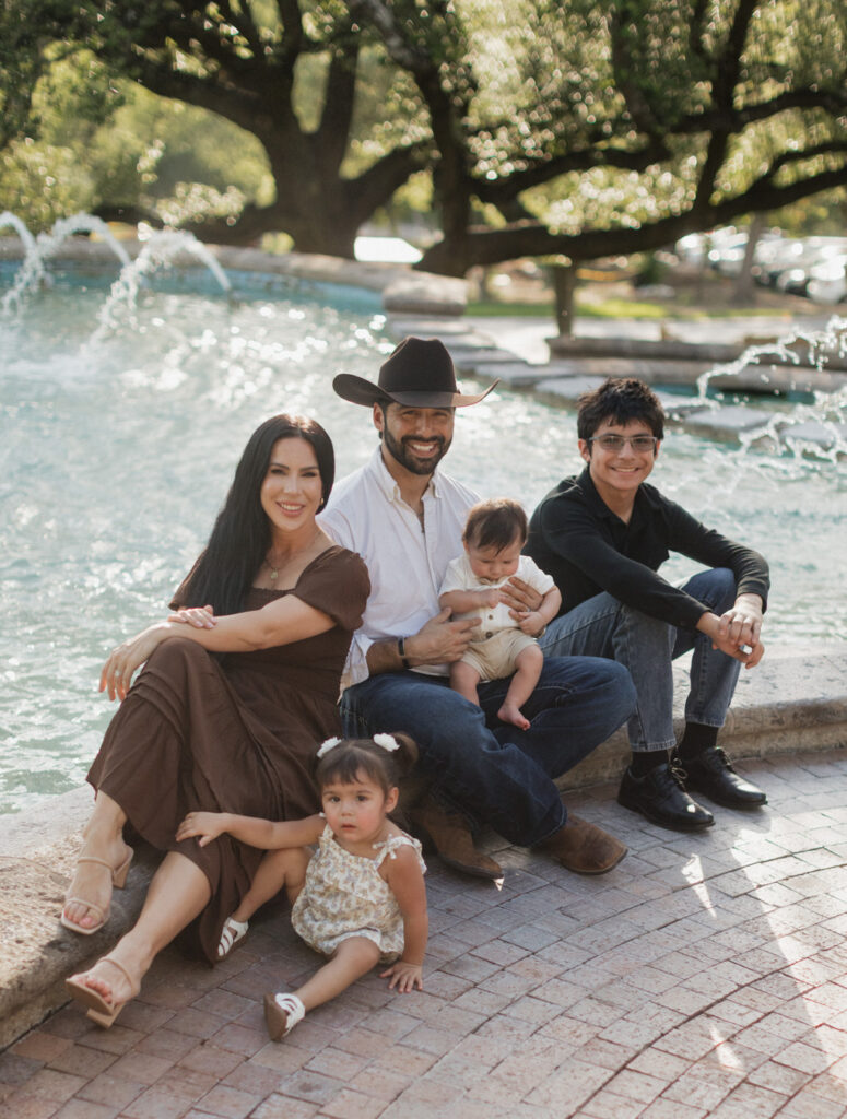 Gorgeous Hispanic family sits at the McNay Art Museum foutnain. They found the right photographer