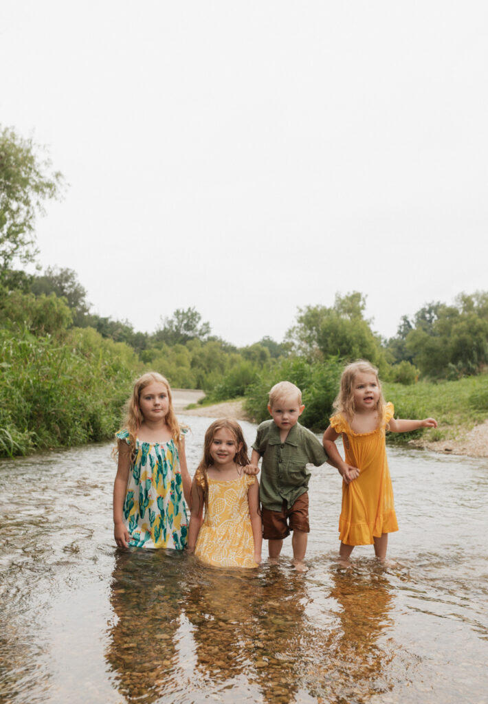 Siblings, three girls and baby brother play walk in the Cibolo Creek, cooling off at the Crescent Bend Nature Park