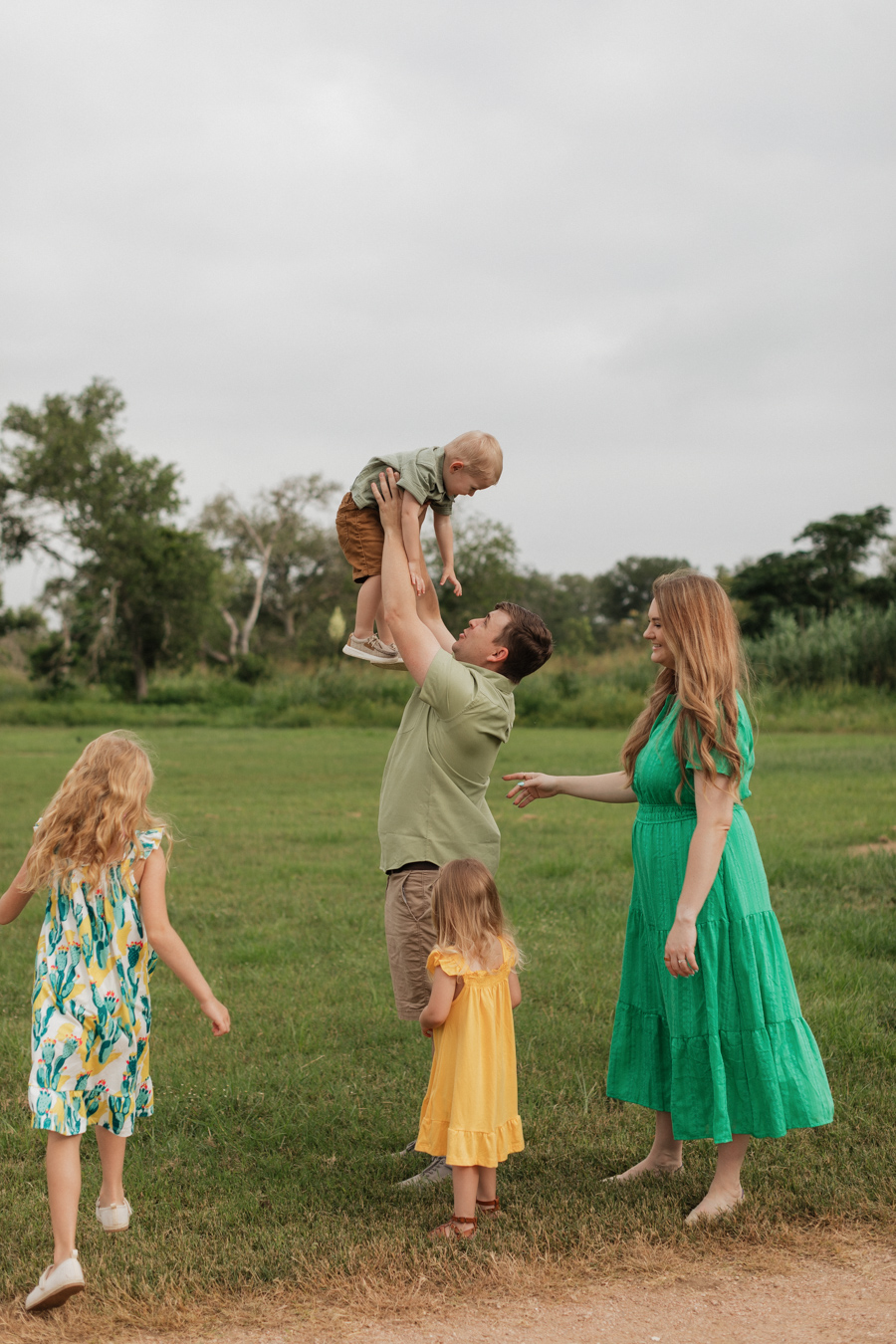 Family photos at Crescent Bend Nature Park in Schertz Texas. They laugh as the children run around them and the father throws his little one up playfully into the air.