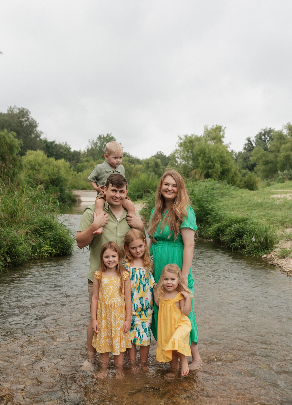 A family beams at the camera, cooling off in the Cibolo Creek in Schertz